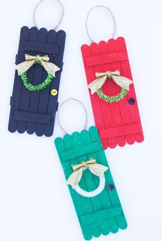 three popsicle christmas door hangers with bows and wreaths on them, all made out of popsicle sticks