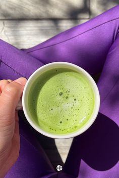 a person is holding a cup of green liquid