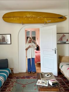 a person standing in a living room with a surfboard on the wall above their head