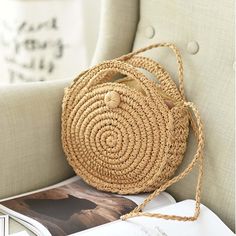 a straw bag sitting on top of a chair next to an open book and magazine