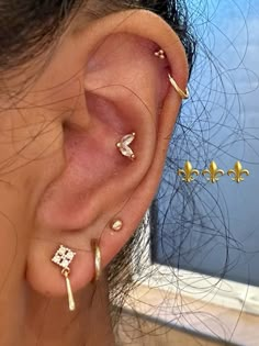 a woman with three different ear piercings on her left ear and the other one is gold