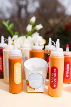 several bottles of condiments on a table with flowers in the background