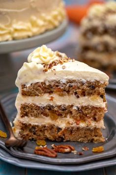 a slice of carrot cake with cream frosting and pecans on a blue plate