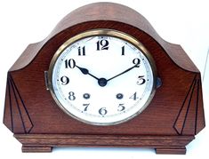 a wooden clock with white face and numbers on the front, sitting against a white background