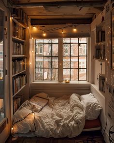 a bed in a room with bookshelves and lights on the windows sill