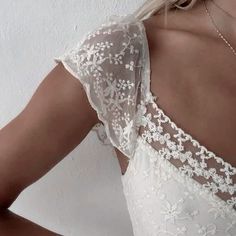 the back of a woman's wedding dress with white lace and beading on it