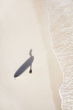 a man riding a surfboard on top of a sandy beach next to the ocean