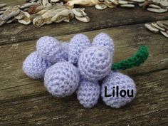 small crocheted flowers sitting on top of a wooden table next to shells and leaves