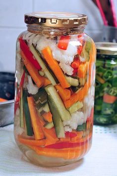 a jar filled with sliced vegetables sitting on top of a table next to other containers