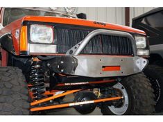 an orange truck with large tires and front bumper