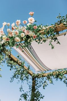 an outdoor wedding ceremony setup with flowers and greenery on the top of the arch