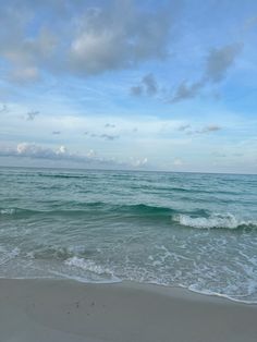 an ocean view with waves crashing on the shore and clouds in the sky over the water