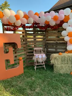 an outdoor area with hay bales and balloons on the fence, including a chair