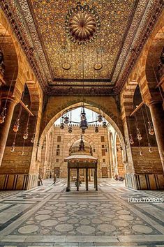 the inside of an ornate building with many pillars and ceiling lights on each side of it