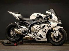 a white and black motorcycle parked next to a wall