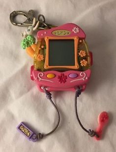 a pink electronic toy with keychain attached to it's side and an lcd screen in the middle