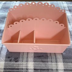 an empty pink box on a checkered tablecloth with three holes in the middle