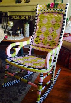 a chair that has been painted pink, yellow and black with an intricate design on the back