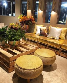 a living room filled with lots of furniture and plants on top of wooden pallets