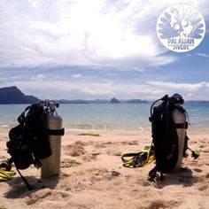 two scuba gear sitting on top of a sandy beach