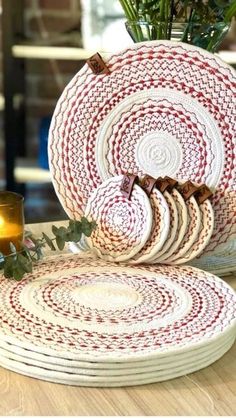 red and white plates sitting on top of a wooden table next to a vase filled with flowers