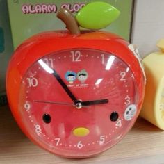 an alarm clock is sitting on a table next to a toy apple and other toys