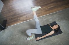 a woman is doing yoga on a mat with her feet up in the air while wearing green shoes