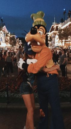 a man and woman hugging each other in front of mickey mouse