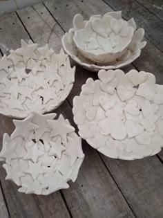 four white bowls sitting on top of a wooden table