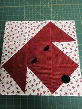 a red and white quilted block with black dots on the bottom, sitting on top of a green cutting board