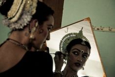 a woman is getting her make up done in front of a mirror with an elaborate head piece