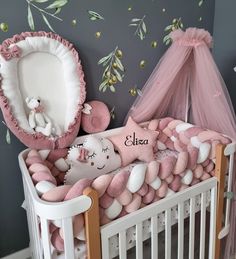 a baby crib with pink and white bedding, stuffed animals and mosquito netting