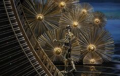 the oscars statue is surrounded by golden balls and sparkley lights in front of an artistic backdrop