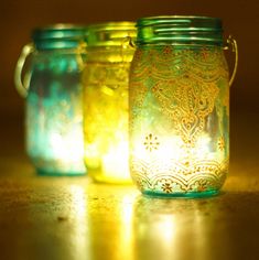 three mason jars sitting on top of a table next to each other with lights in them