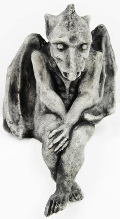 a black and white photo of a gargoyle sitting on the ground with its head down