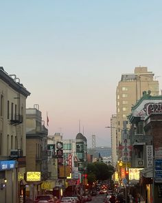 a city street filled with lots of traffic next to tall buildings in the evening sun