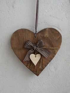 a wooden heart hanging on a wall with a bow around it's neck,