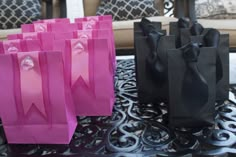 pink and black paper bags sitting on top of a metal table next to a couch