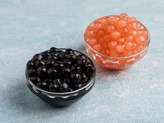 two bowls filled with blackberries on top of a blue countertop next to each other