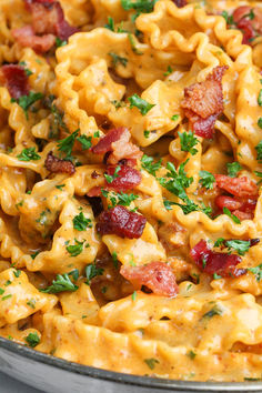 a close up of a plate of pasta with bacon and parsley on the side