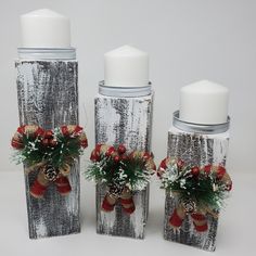 three candle holders are decorated with red and white flowers, pine cones, and bows