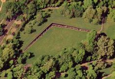 an aerial view of a grassy area with trees and grass in the foreground,