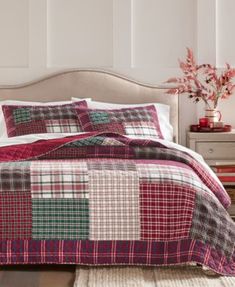 a bed with red, green and white plaid comforter set on top of it