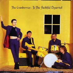 the cranberries are posing for a photo in front of a yellow wall with their instruments