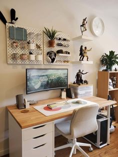 a desk with a computer on top of it next to a shelf filled with figurines