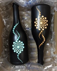 two black vases with designs painted on them