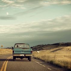 an old pick up truck driving down the road