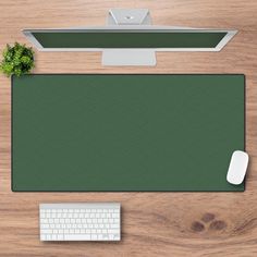 a desk with a keyboard, mouse and computer monitor on top of it next to a plant