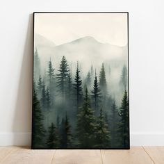 a forest scene with pine trees in the foreground and mountains in the background on a black framed canvas