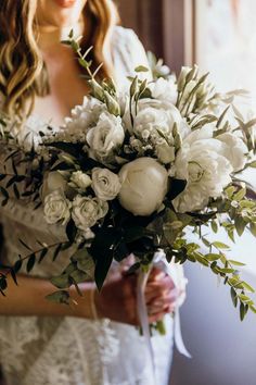 a woman holding a bouquet of white flowers